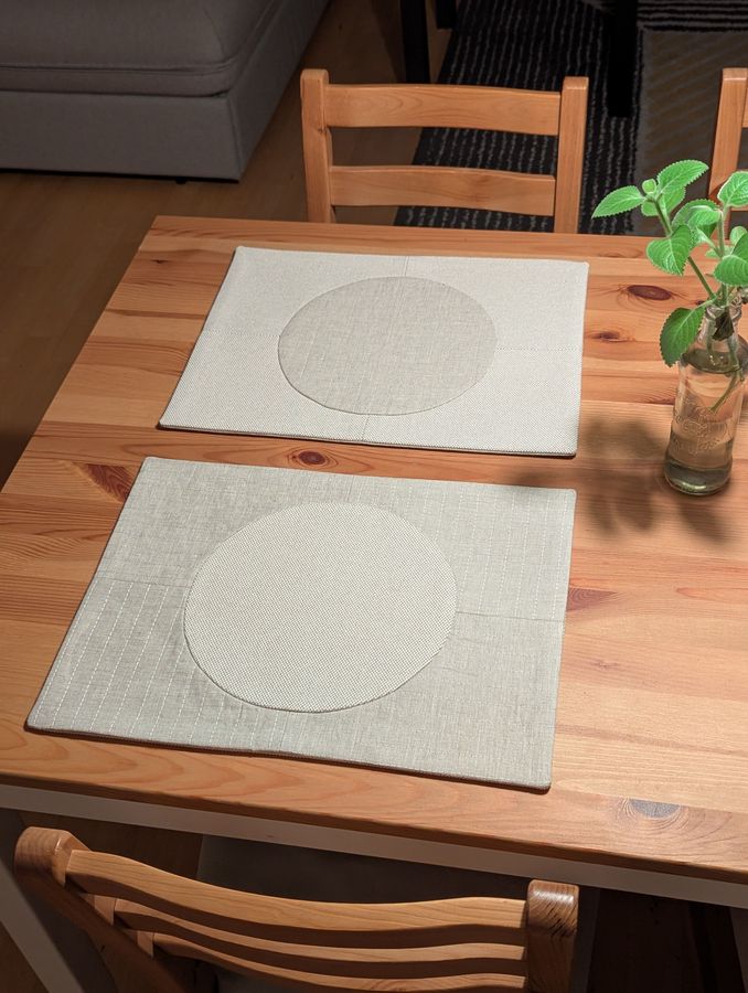 A pair of linen placemats with a circle on a wooden table